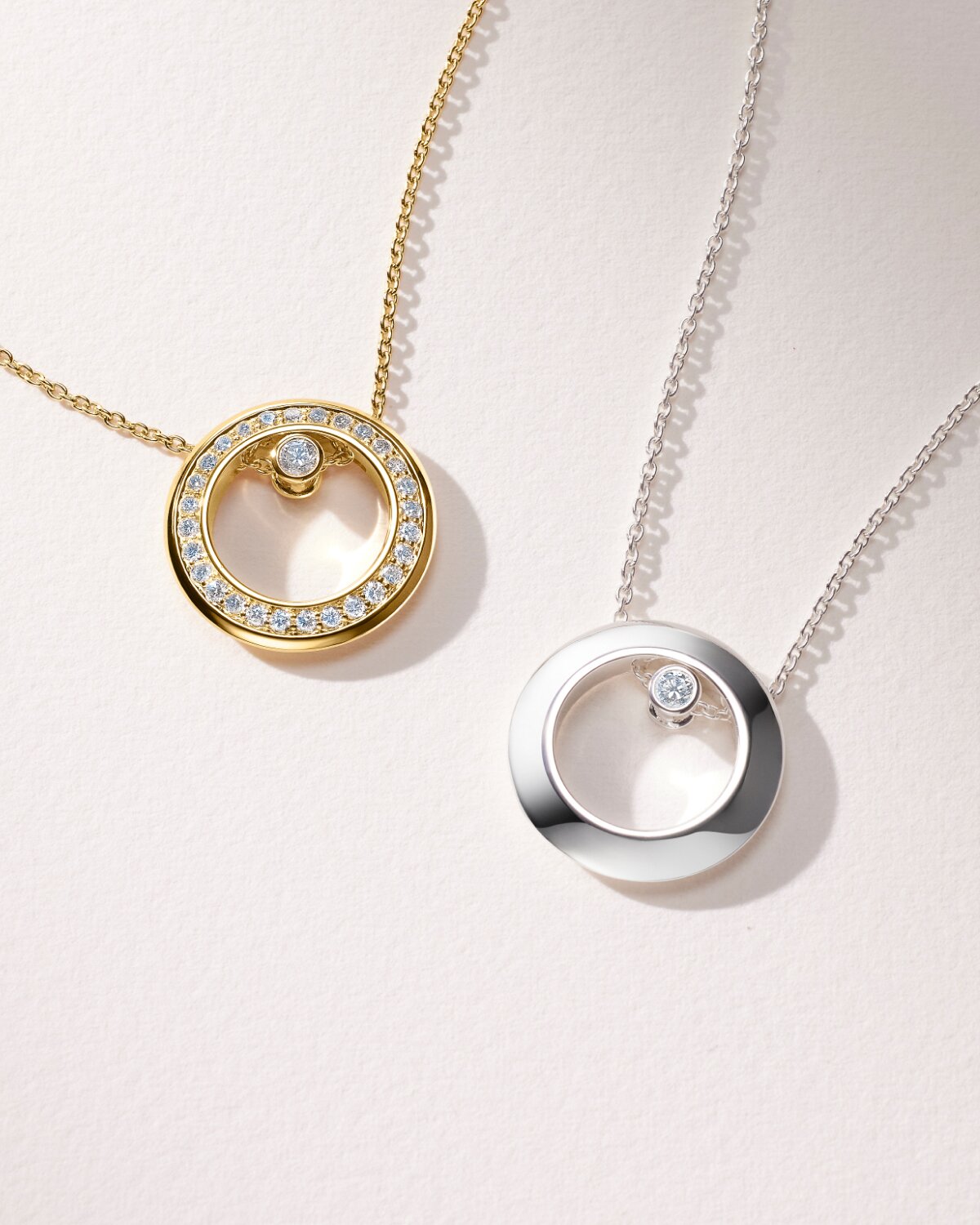 Gold tone women's Ono Necklace with lab grown diamonds next to a sterling silver Ono necklace with one lab grown diamond.