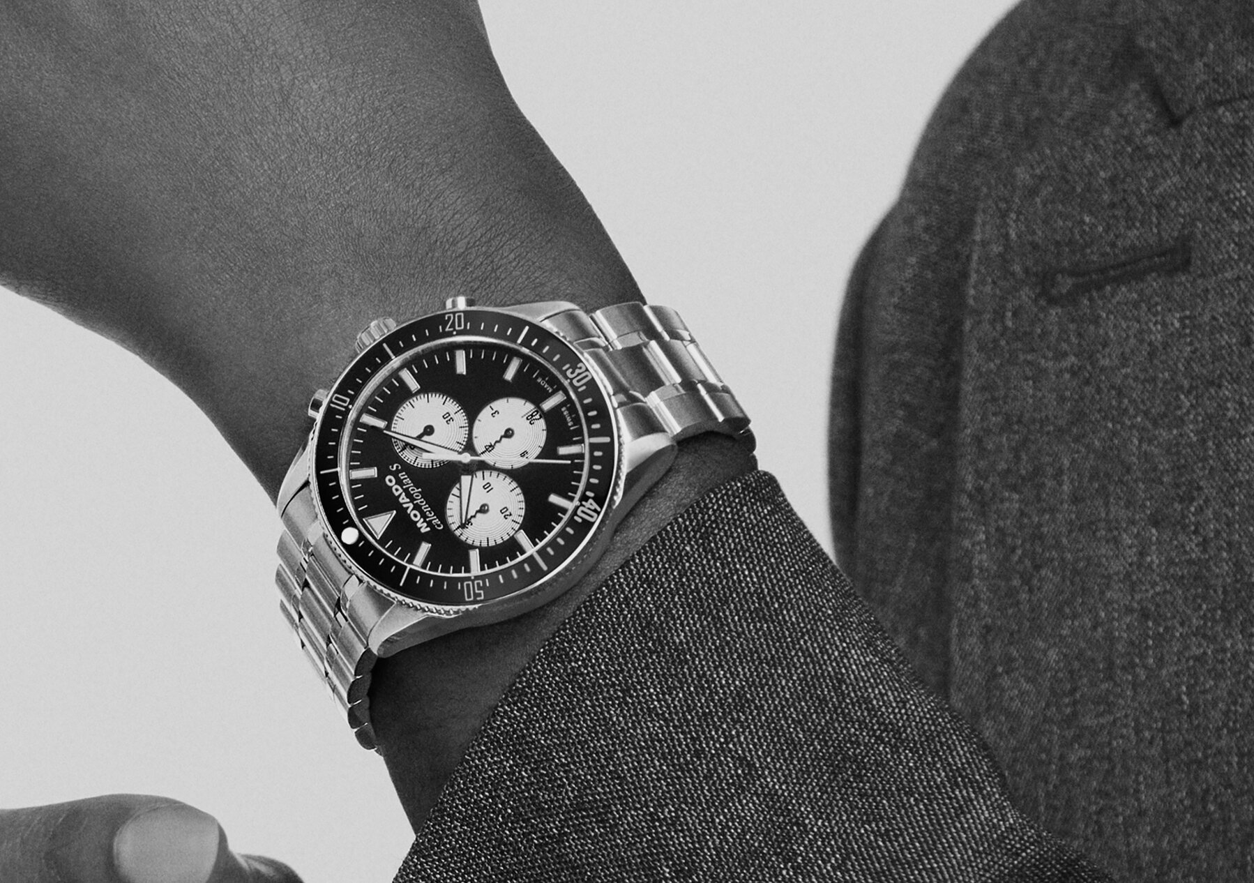 Man in a grey coat wearing the Heritage Calendoplan S watch with stainless steel bracelet and black chronograph dial.