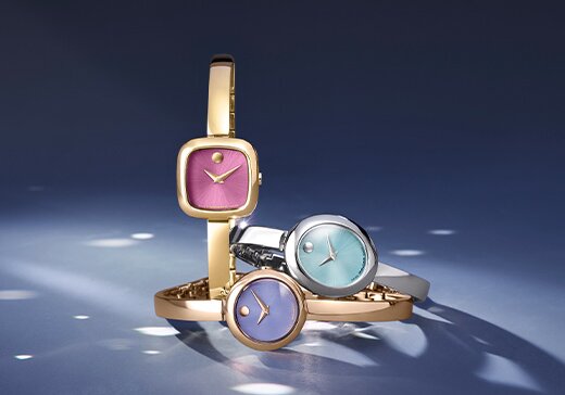 Three Museum Bangle watches: gold tone with pink square dial, silver with blue oval dial and rose gold tone with purple circle dial.