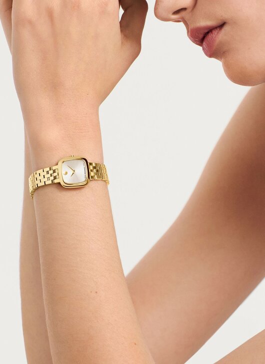 Woman wearing the gold tone Museum Classic bracelet watch with square dial.