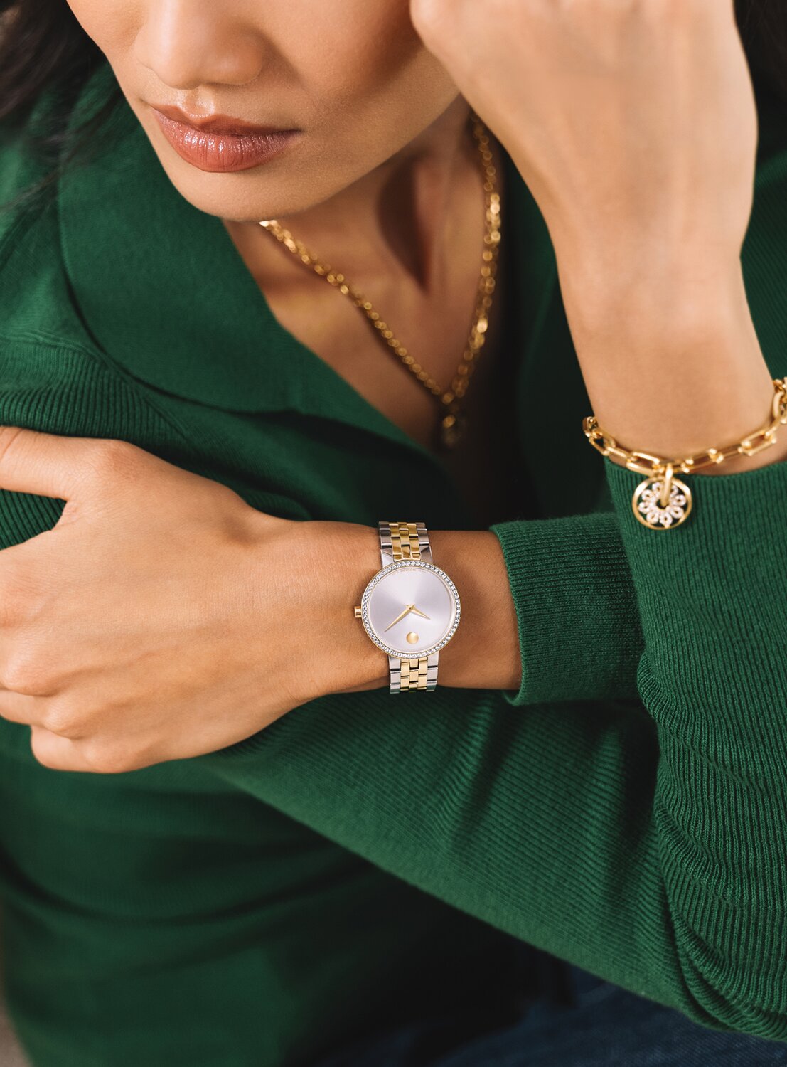 Woman in a green sweater wearing a two tone Museum Classic watch with lab grown diamonds. She is also wearing the gold tone Fleur necklace and bracelet.