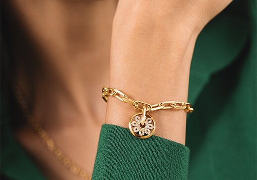 Gold tone bracelet with fleur charm on a women's wrist