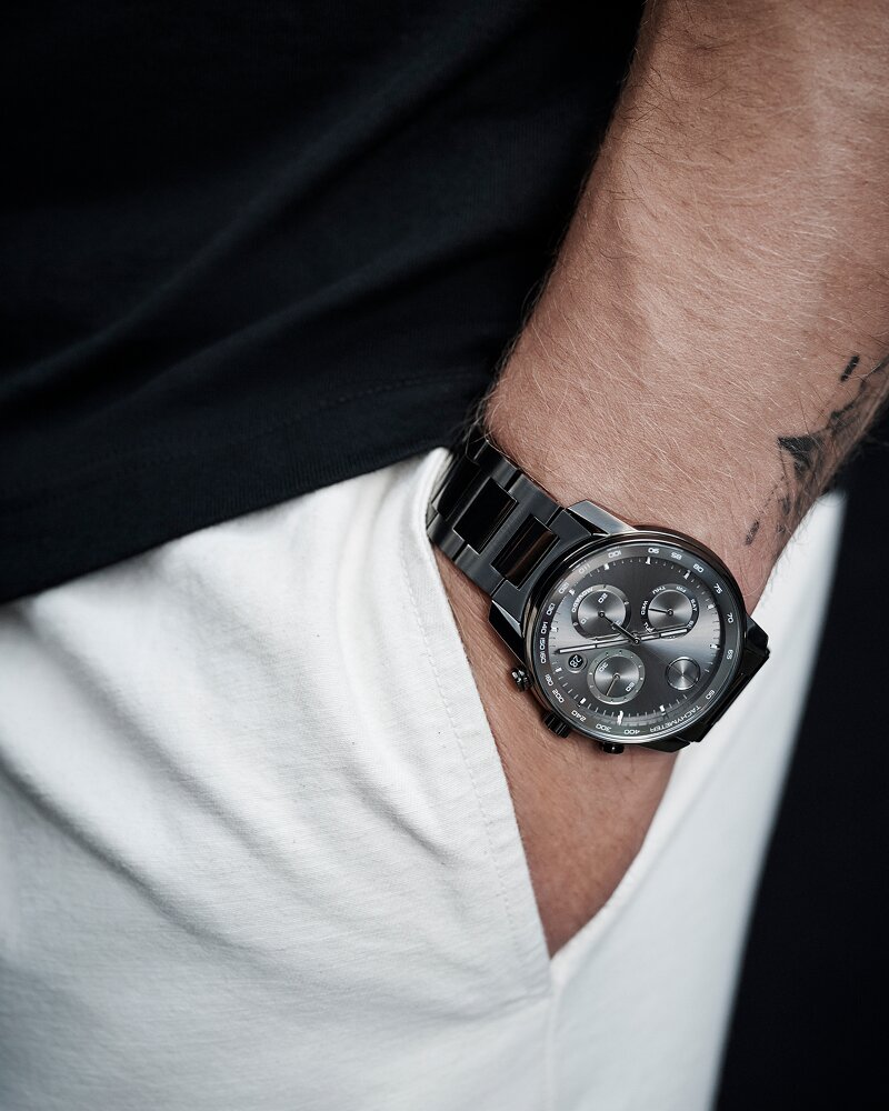 Christian McCaffrey's hand in the pocket of his white pants while wearing a grey BOLD Verso Chronograph watch