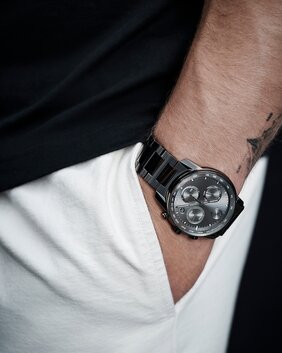 Christian McCaffrey's hand in the pocket of his white pants while wearing a grey BOLD Verso Chronograph watch