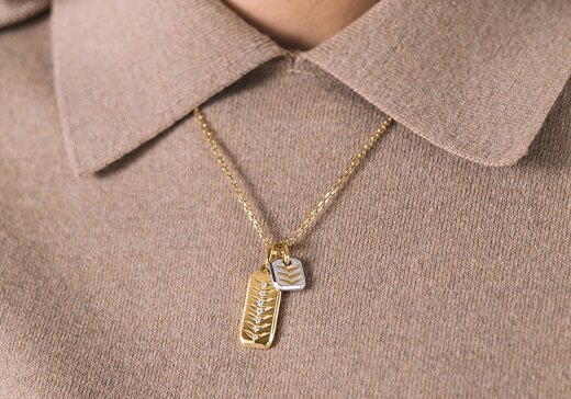 Two tone chevron charm necklace on a brown collared shirt