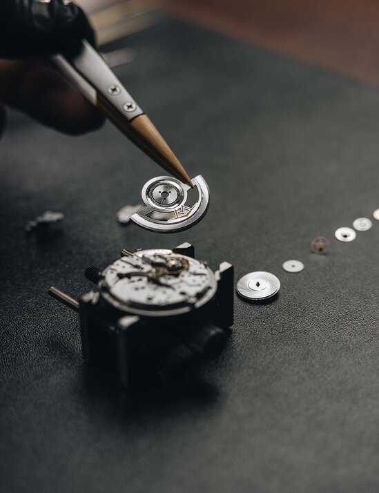 Close up of someone assembling the automatic movement with tweezers.