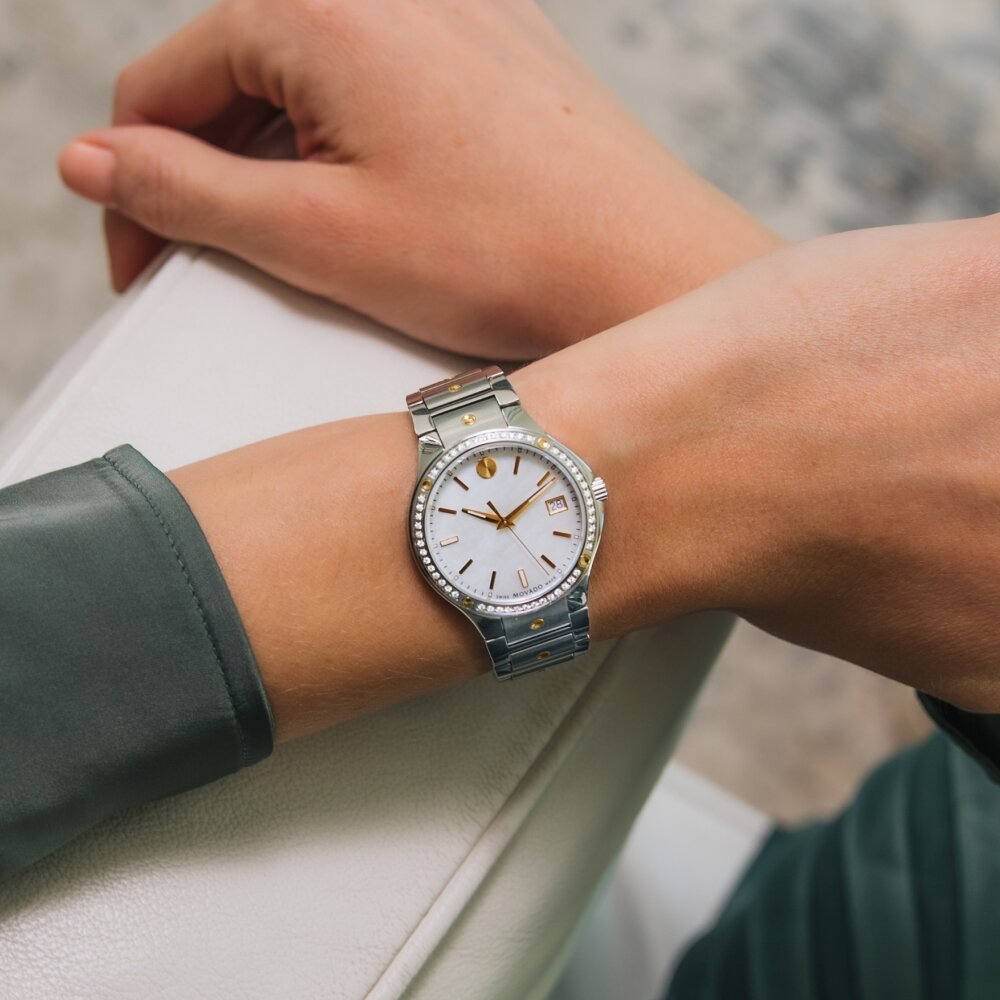 Woman wearing a Movado SE watch with white mother of pearl dial, diamond bezel and silver bracelet.