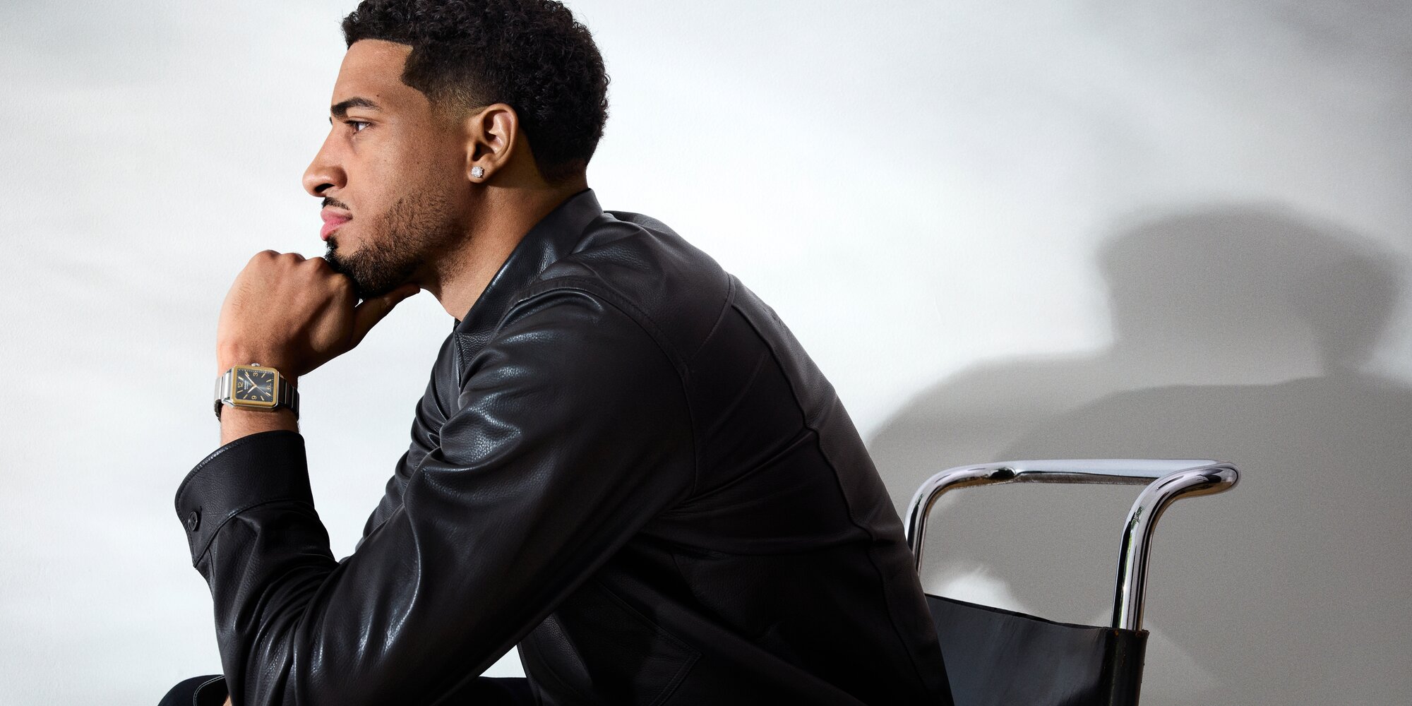 Tyrese Haliburton, leaning on his hand, wearing a black leather shirt and the stainless steel 1917 bracelet watch with square dial.