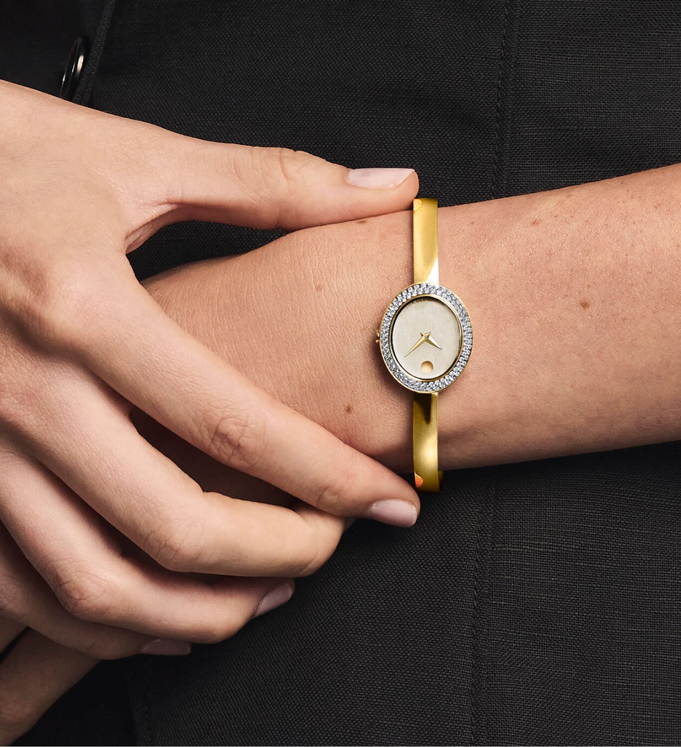 Woman wearing a museum bangle watch with oval dial and lab grown diamond bezel.