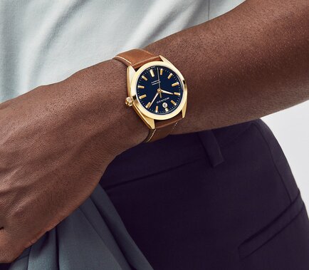 Man wearing the Heritage Datron watch with brown leather strap and blue dial.