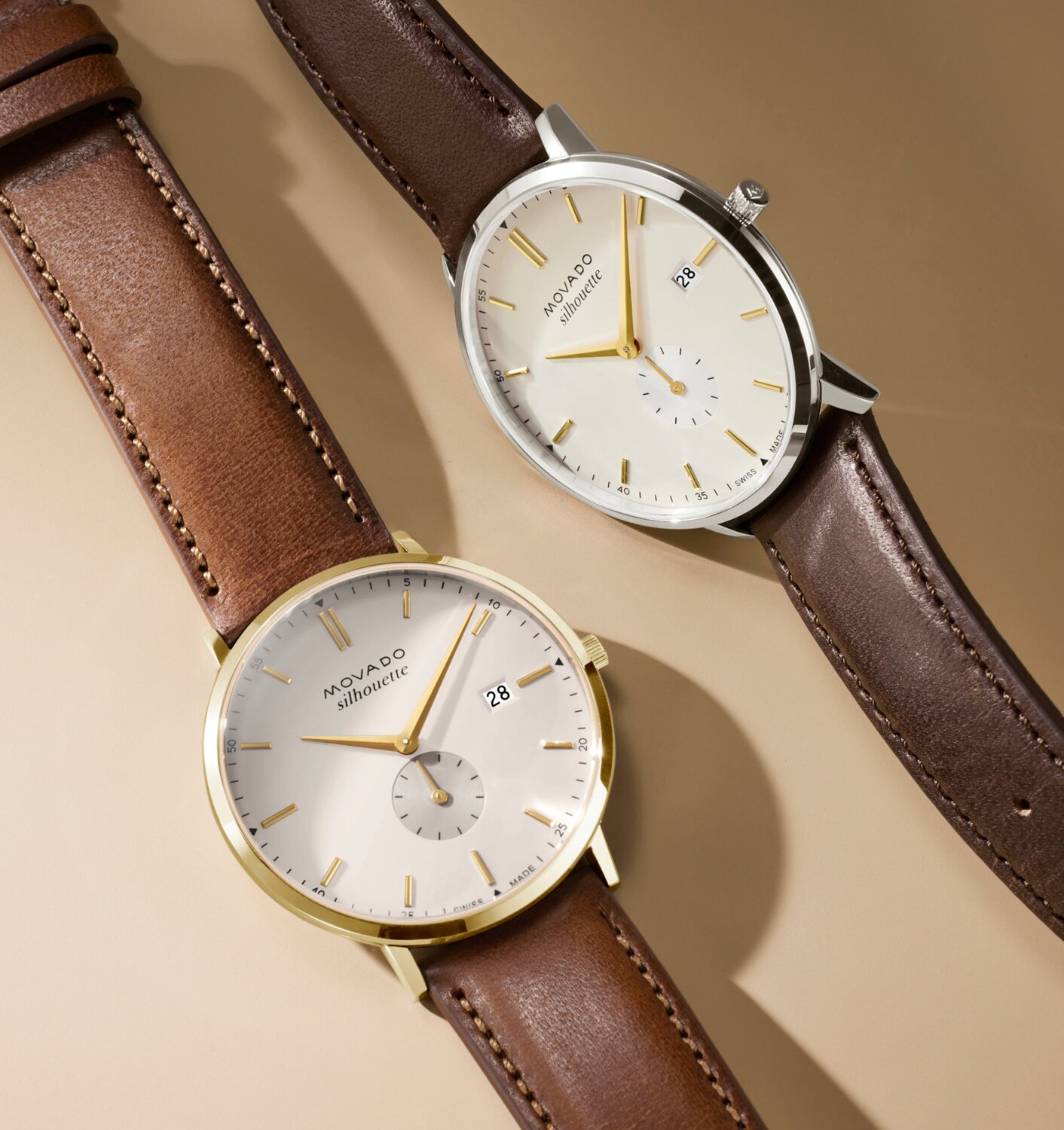 Two Heritage Series Silhouette watches laying next to each other. Both have a brown strap and white dial with gold tone accents.