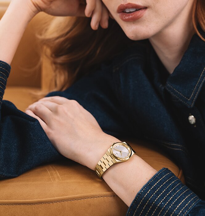 Woman in a denim shirt wearing the gold tone Movado BOLD Quest Mini Watch.