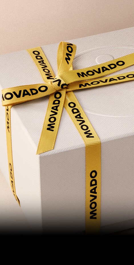White gift box wrapped in yellow ribbon with Movado branding in black font. 