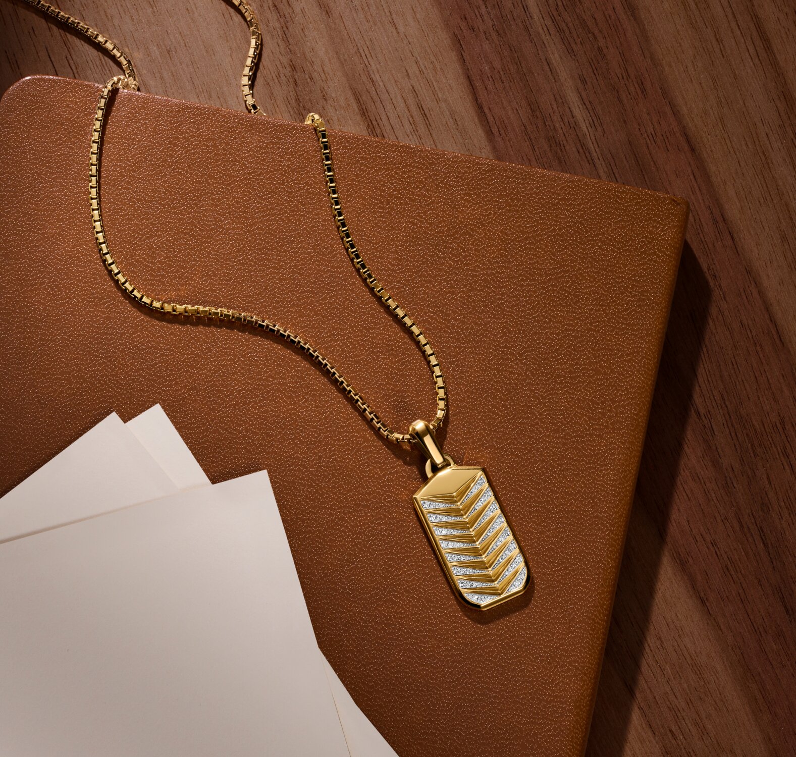 Men's M Chevron Necklace laying on a notebook