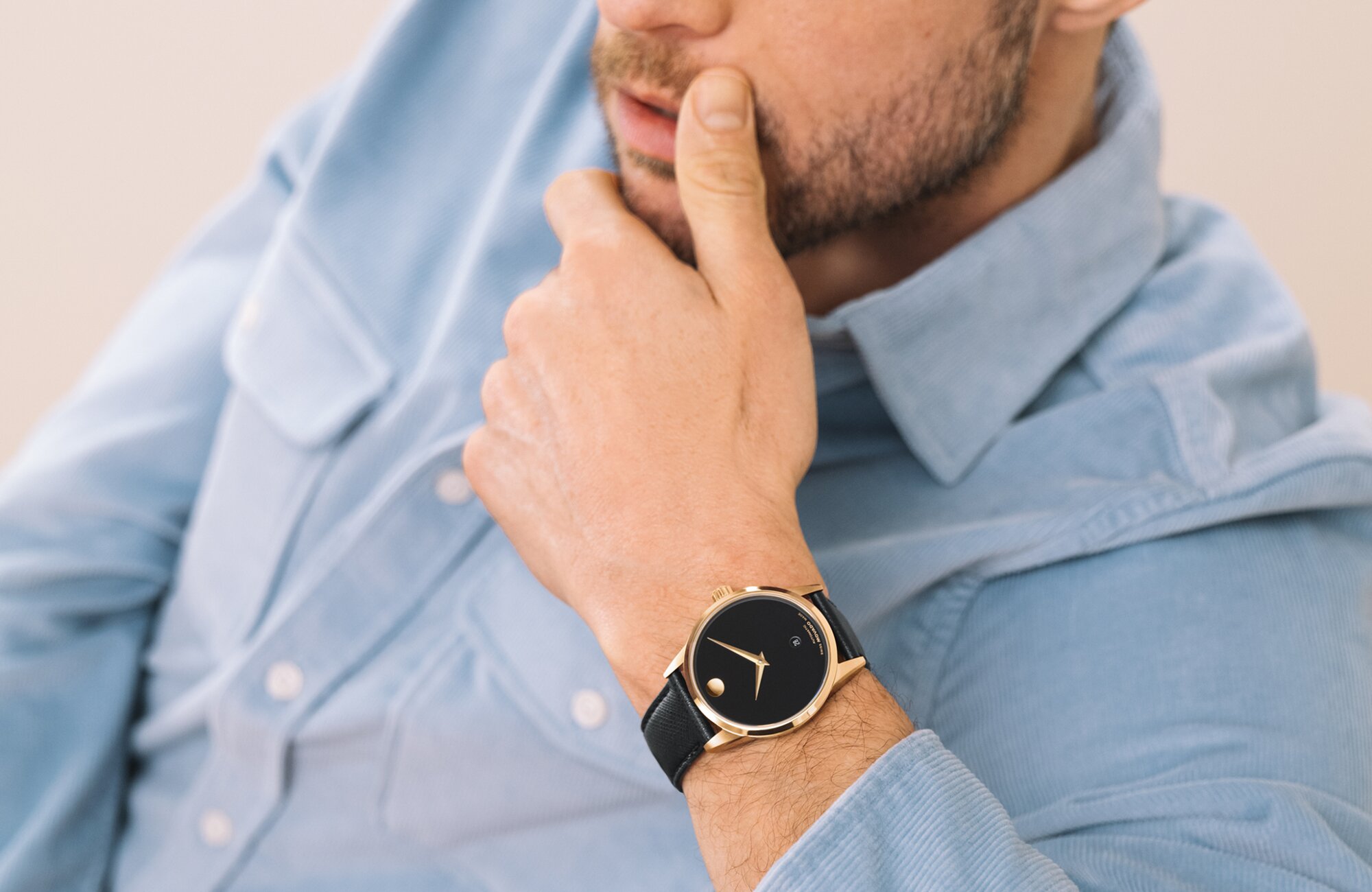Man in a blue button down wearing the Museum Classic watch with black strap and dial with his head leaning on his hand.