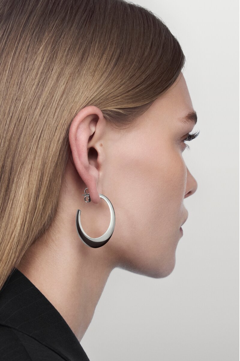 Woman wearing the sterling silver Curve Oval Hoop earring.