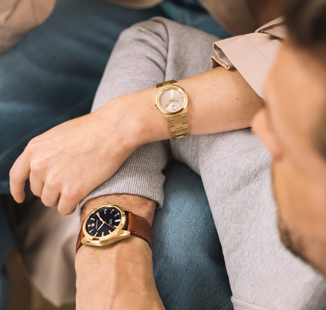 Woman wearing a gold tone BOLD Quest Mini watch with her arm on a man wearing the Heritage Datron watch with brown leather strap and blue dial.
