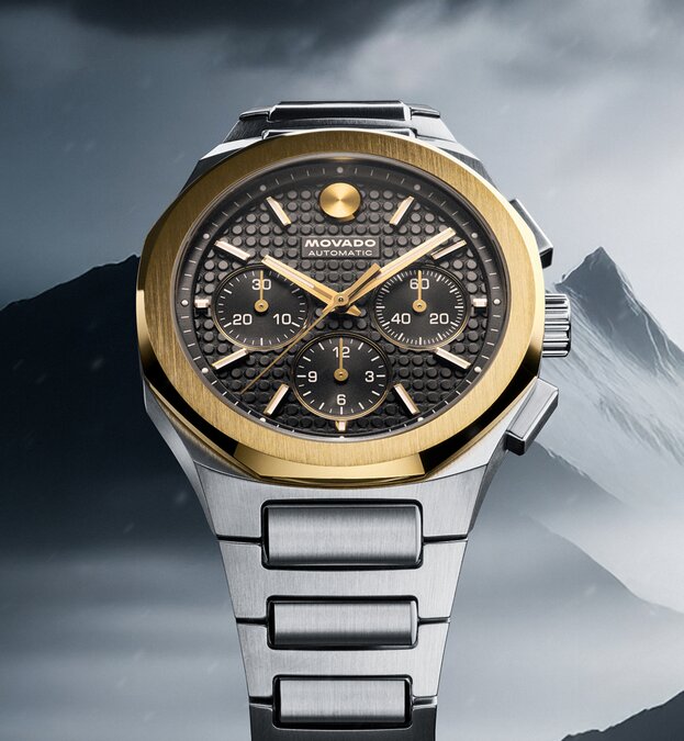 Alta Centurion Chronograph watch with stainless steel bracelet, grey dial and 18k gold bezel in front of a mountain.