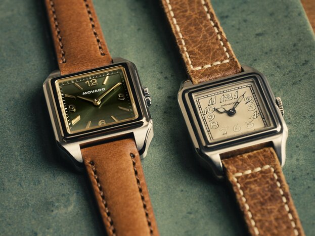 Original Heritage 1917 watch with brown strap and beige dial laying next to the new Heritage 1917 watch with brown strap and green dial.