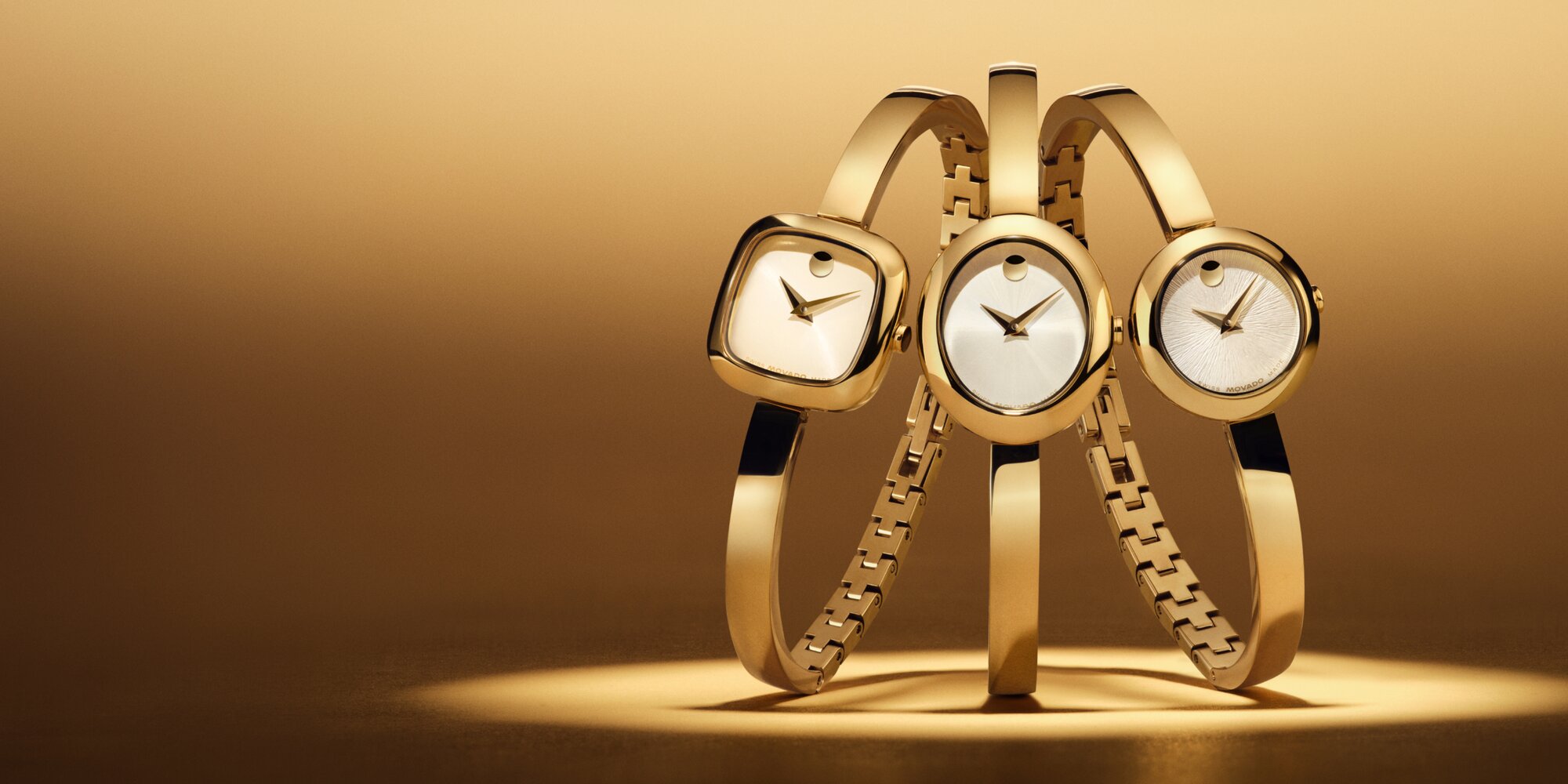 Gold tone Museum Bangle with a circle dial, next to a, Gold tone Museum Bangle with a square dial, next to a, Gold tone Museum Bangle with an oval dial.