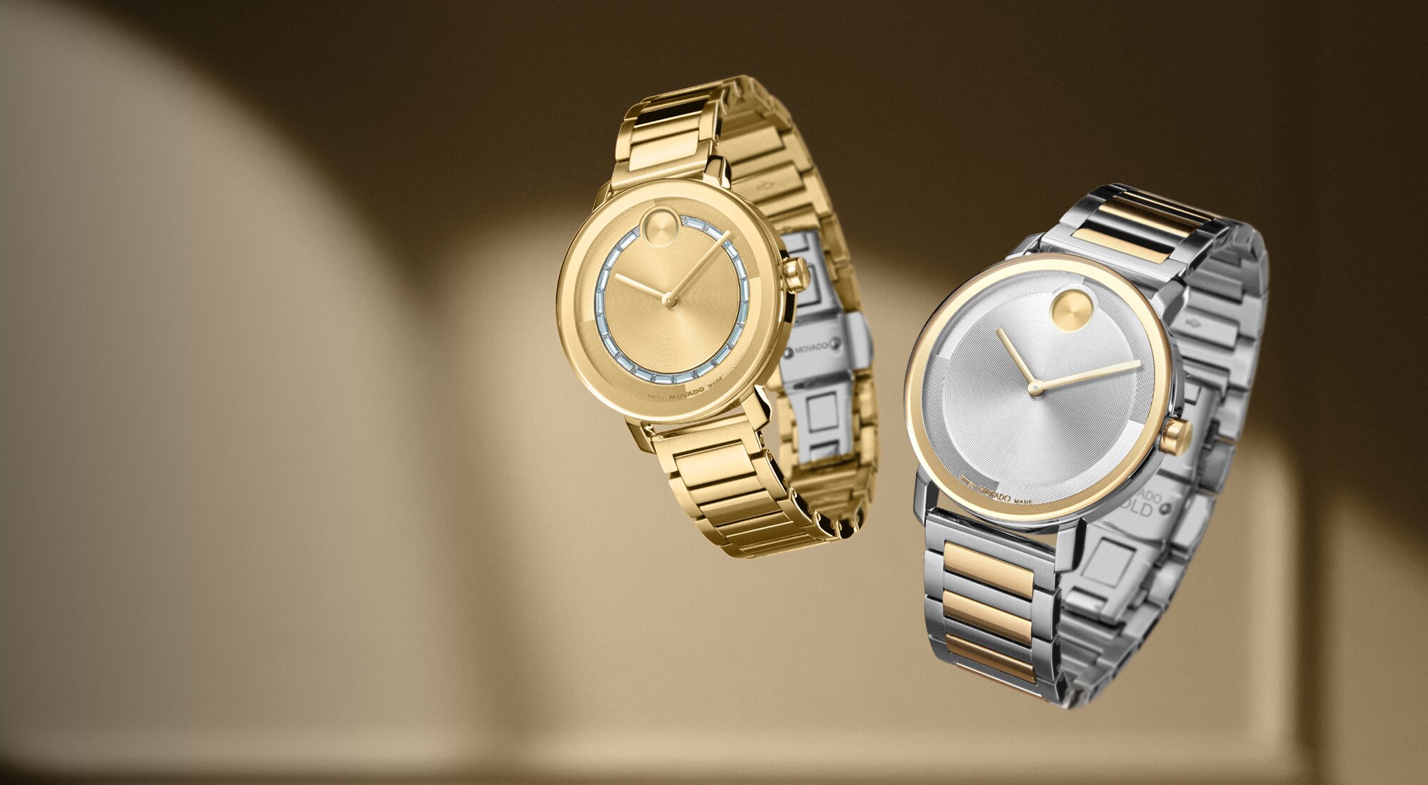 Women's BOLD Evolution 2.0 gold tone watch with crystals floating next to a Men's two toned BOLD Evolution 2.0 watch.