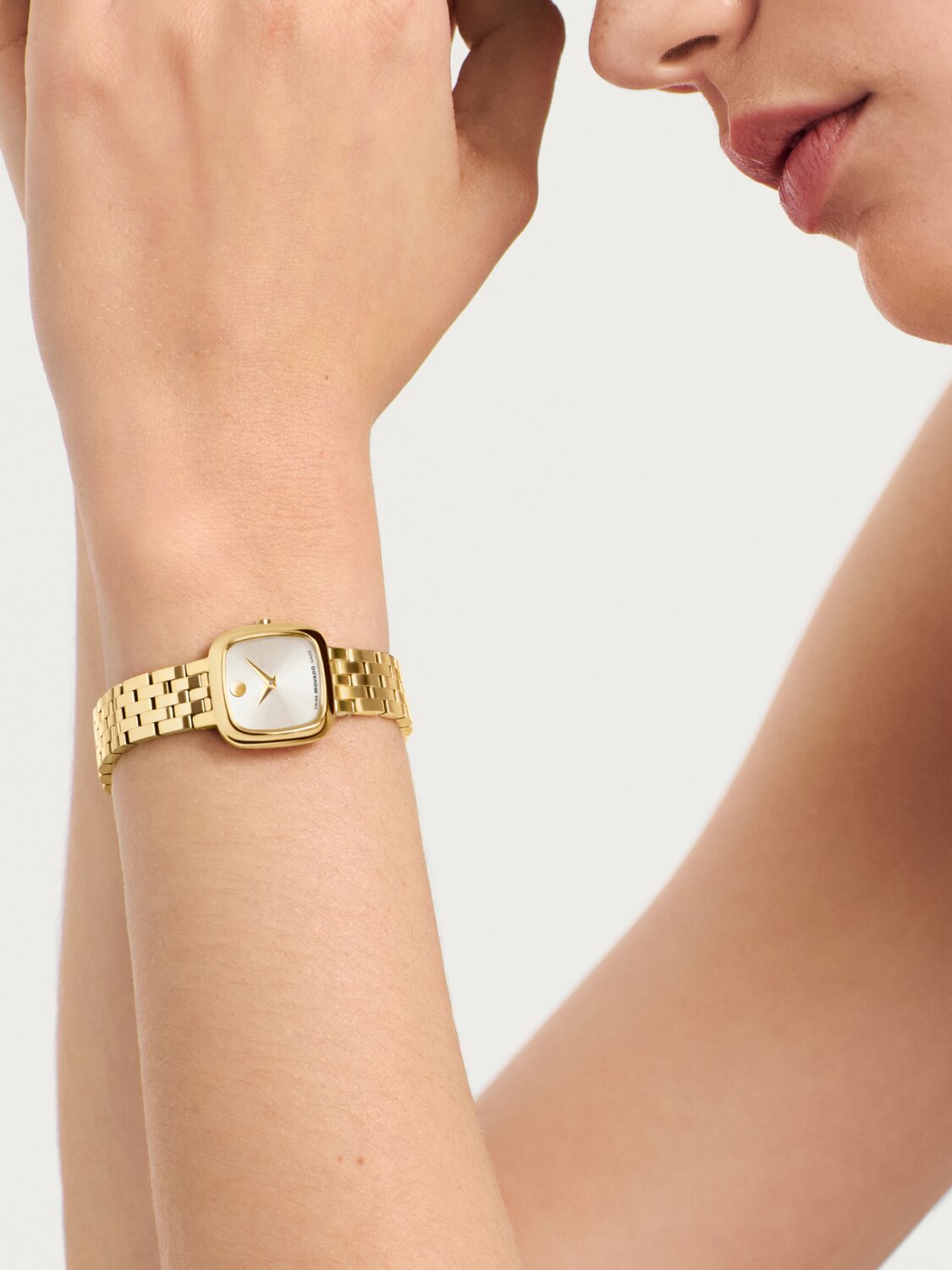 Gold tone Museum Classic bracelet watch with square dial on a woman's wrist.