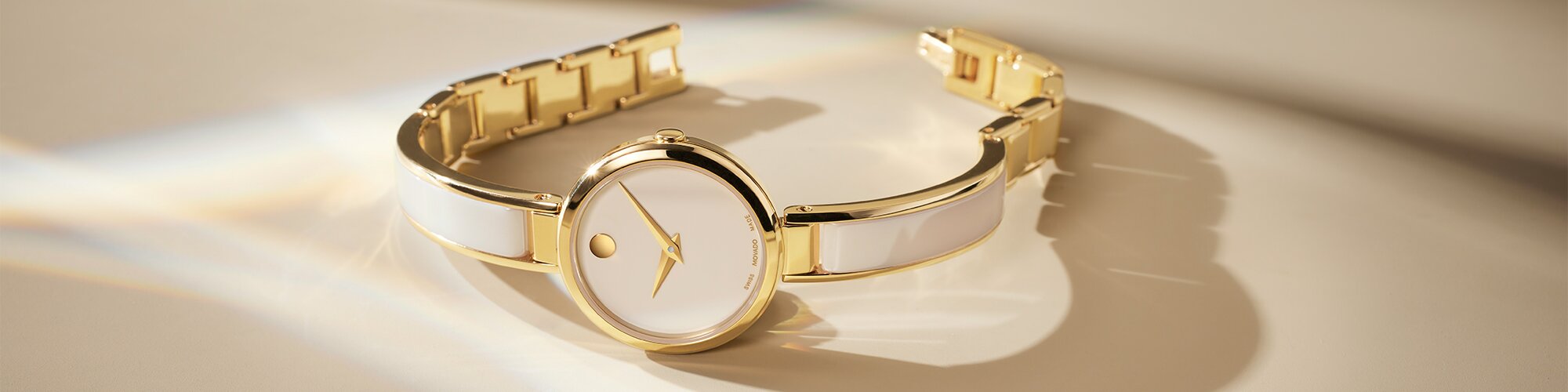 Gold tone Moda bangle watch with taupe ceramic inlay within the bangle and taupe dial.
