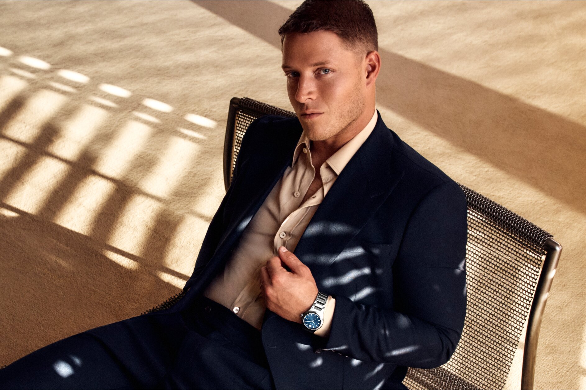 Christian McCaffrey sitting in a chair, wearing a suite and the Museum Imperiale watch with stainless steel bracelet and blue dial.
