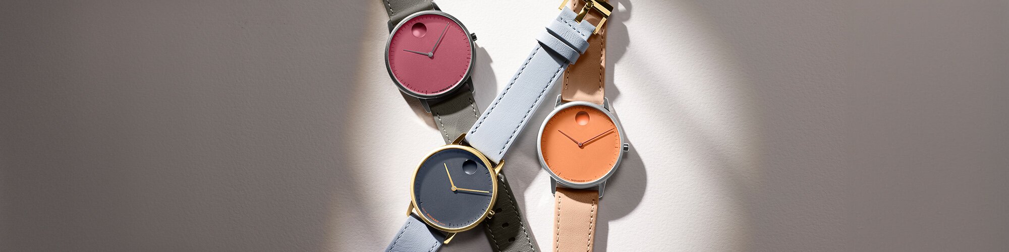 Movado Face watches with leather straps. Grey strap with pink dial, blue strap with blue dial and orange strap with orange dial