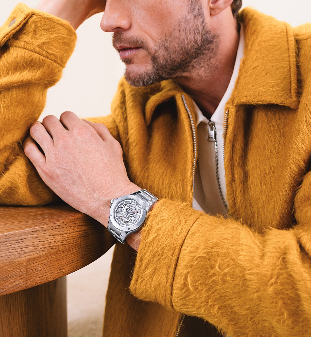 Man in a yellow jacket wearing the stainless steel Alta watch with skeleton dial.