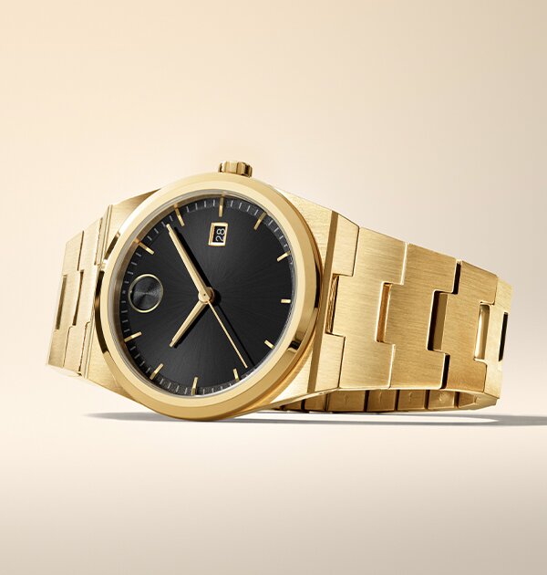 Movado BOLD Quest gold plated bracelet watch with black dial laying on its side