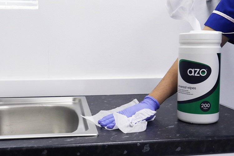A nurse cleaning a countertop with Azo Universal wipes