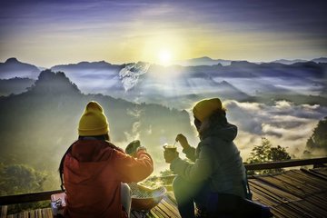 Cross Country Education color photo of two people sitting on a mountaintop in cold weather.