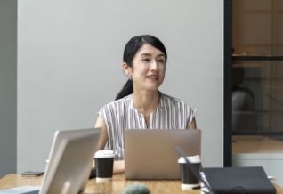 Cross Country color photo of woman looking up over laptop screen.          