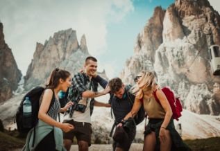 Cross Country color photo of four people with craggy rocks in background.                  