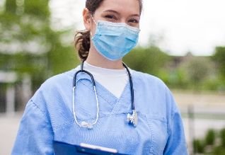 Cross Country color photo of female healthcare practitioner wearing a face mask and scrubs with stethoscope around the neck.          