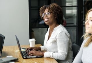 Cross Country color photo of woman working at desk with computer keyboard.              