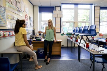 Cross Country Education color photo of two teachers talking.