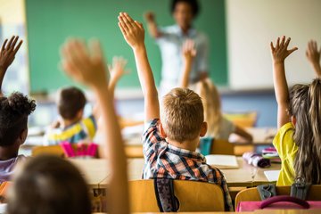 Cross Country Education color photo showing students with their hands raised.