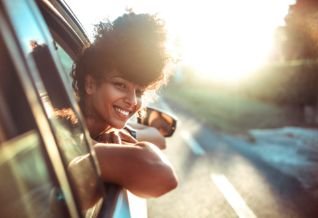 Cross Country color photo of young woman with head out car window.          