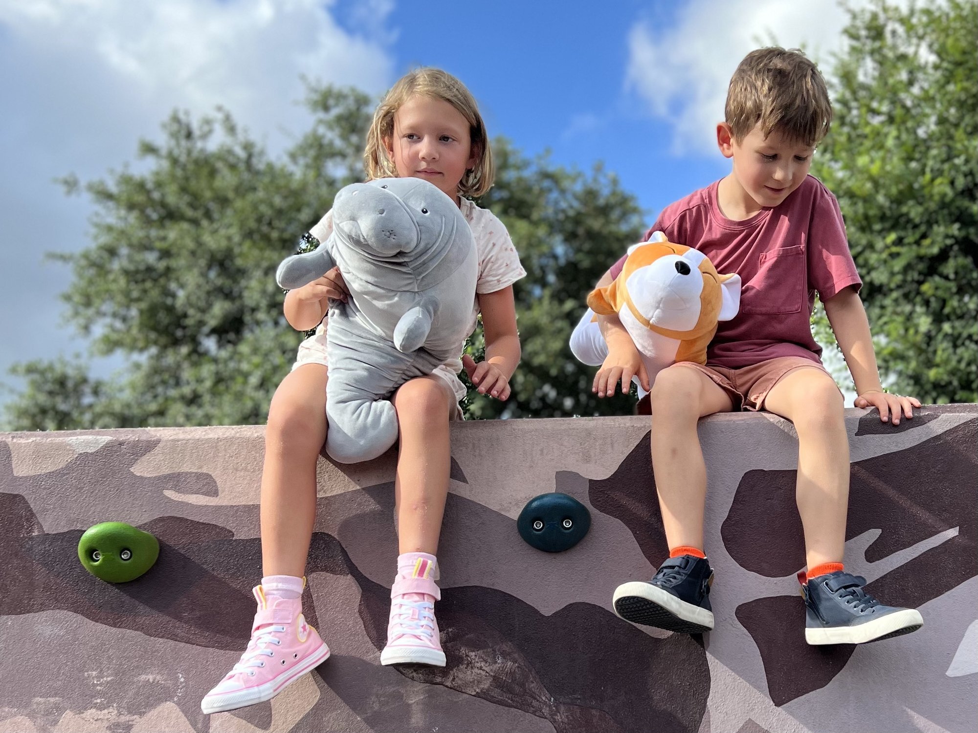 Two kids smiling and holding their Snoozimals outdoors