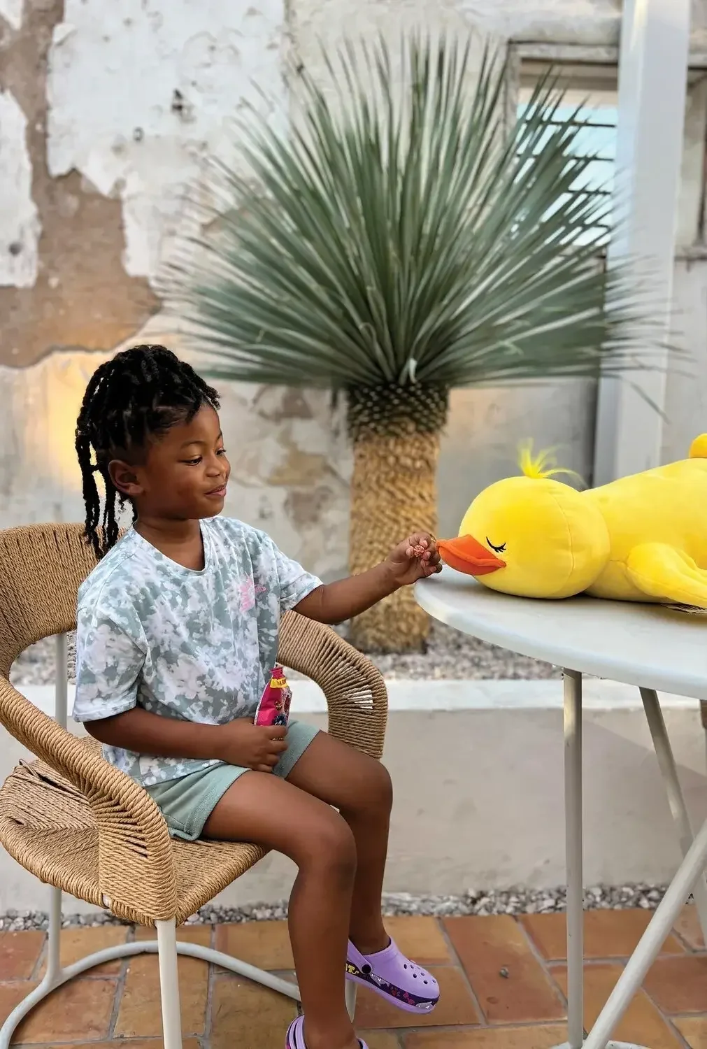 A girl gently touching a giant yellow rubber duck plush toy at Go! Toys and Games