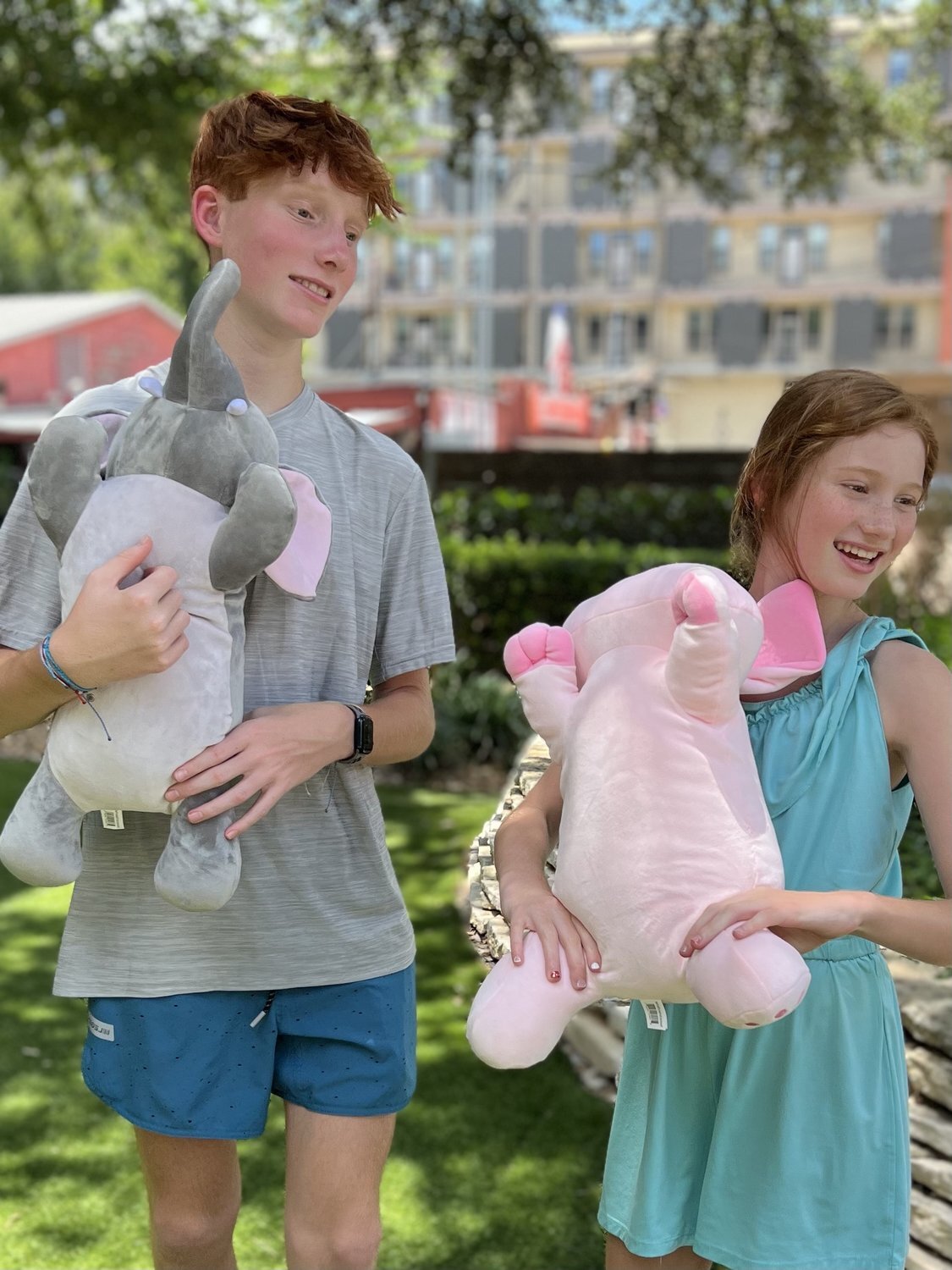 Two kids sitting outside with their Snoozimal plush friends