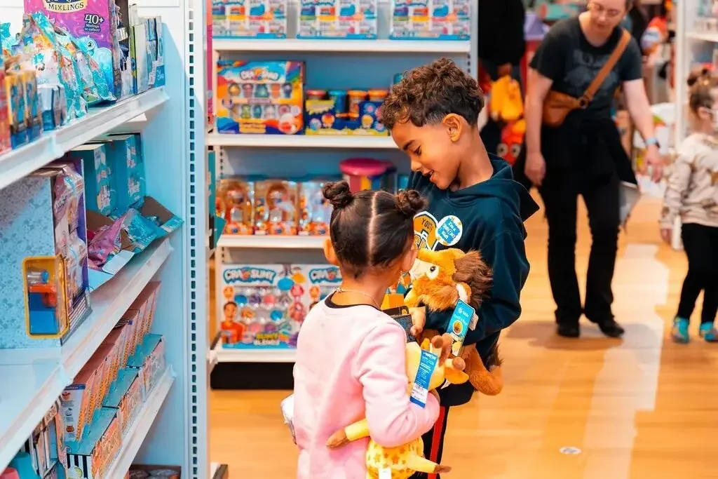 Two kids browsing stuffed animals and toys on colorful shelves at Go! Toys and Games