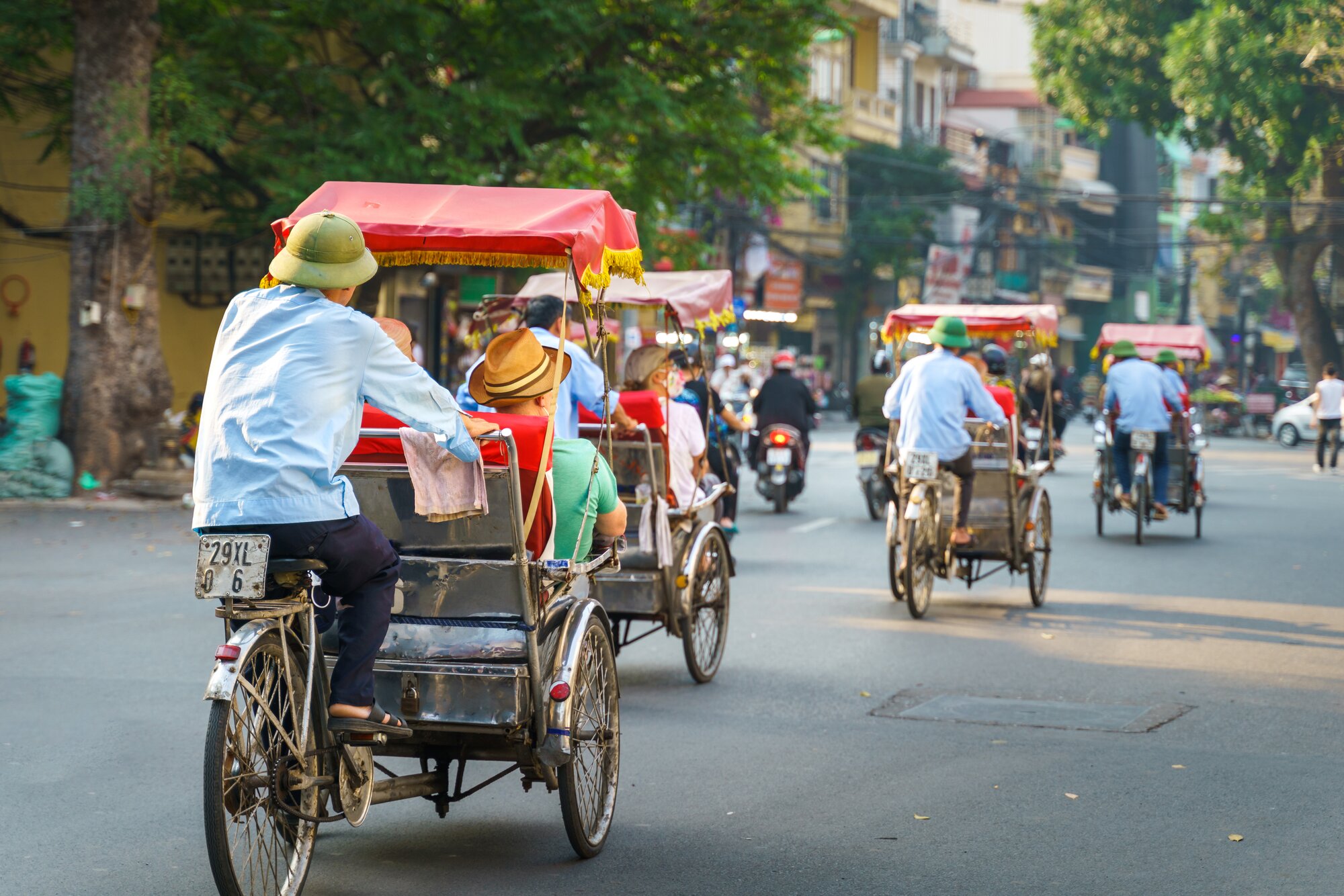 Cyclo driver taking tourist visiting old quarter on street in Hanoi