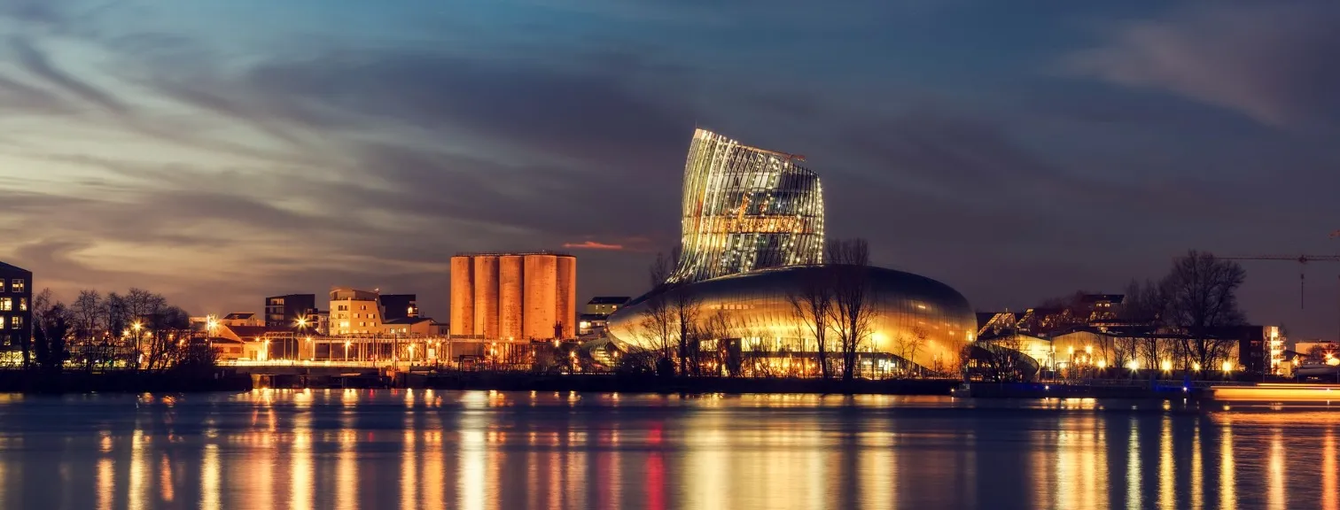 La Cité du Vin museum illuminated at dusk along the Garonne River in Bordeaux, France