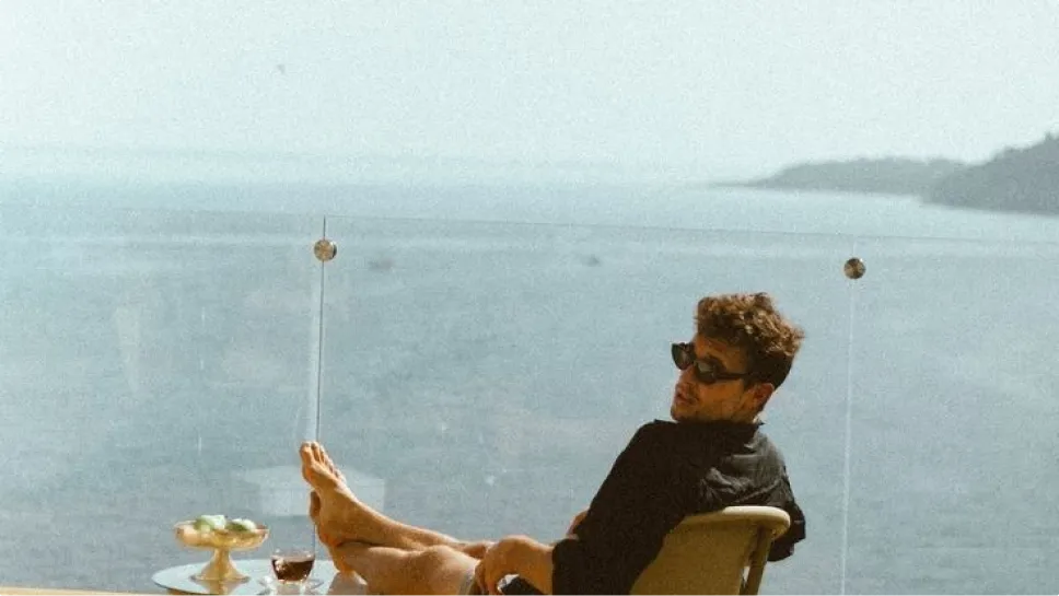 Man enjoying a drink on a terrace overlooking a lake