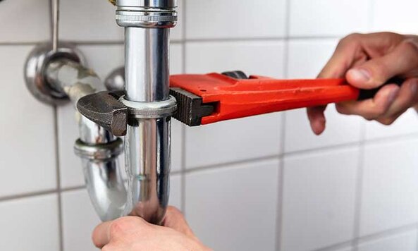 Plumber adjusting pipe under the sink.