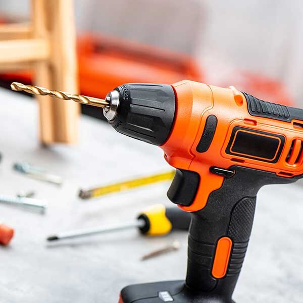 An orange and black drill sits during a DIY project.