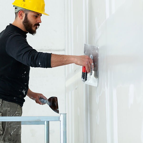A contractor plasters drywall.